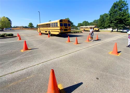 bus driving through safety cones in a parking lot 